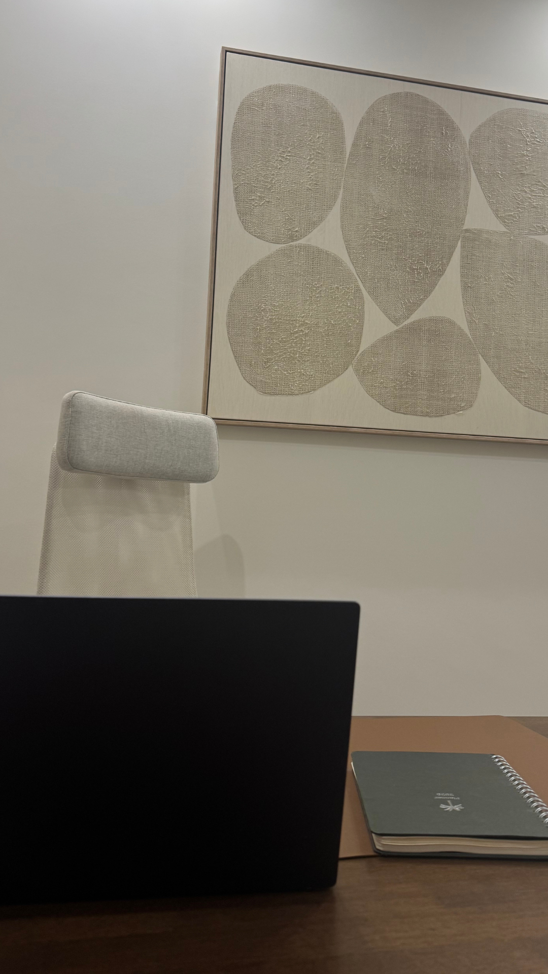 Detalle del despacho con escritorio, silla y cuadro en tonos naturales