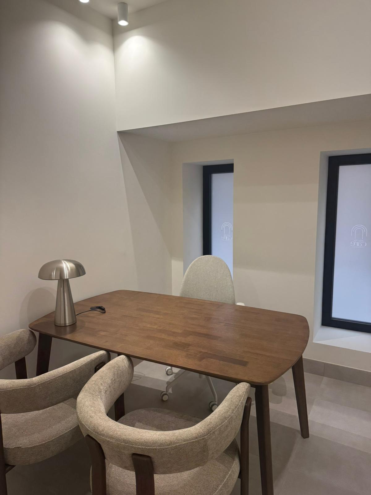 Mesa y sillas de la consulta junto a las ventanas